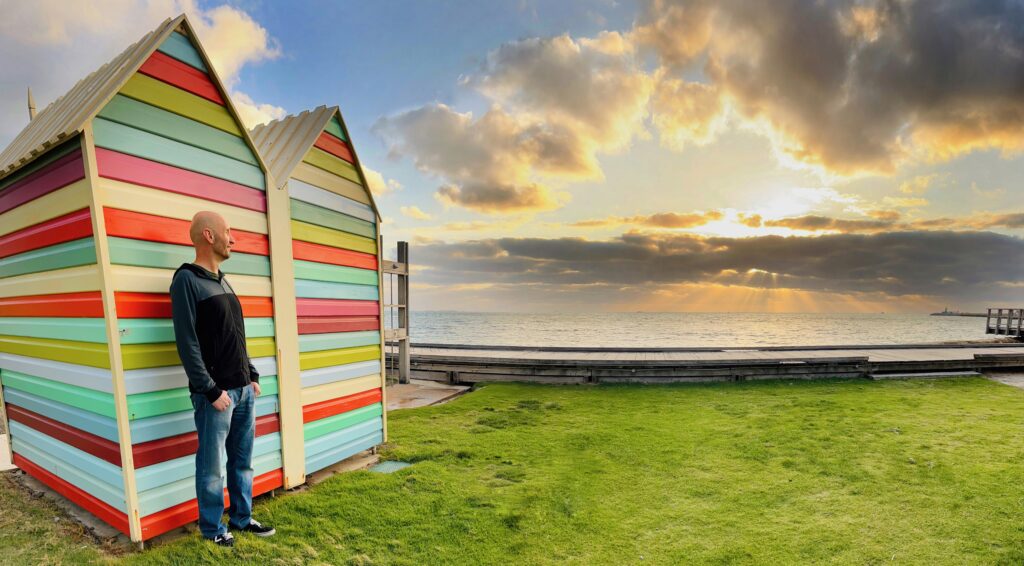 A photo of Dave in front of both a colourful wall and sunset at Bather's Beach.